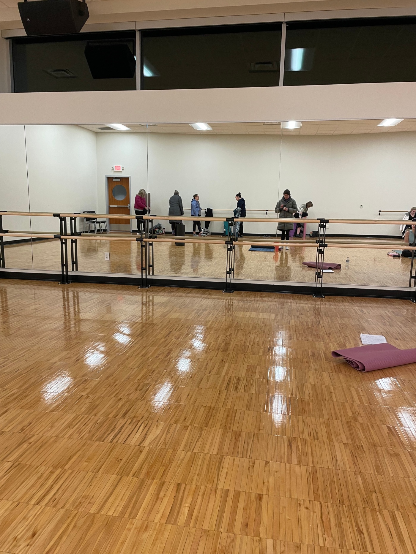 fitness studio with wood floors and barre in front of room before mirror